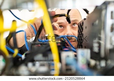 Young programmer adjusting cryptocurrency mining rig to optimal operational settings. High quality photo