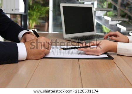 Businesspeople working with contract at wooden table indoors, closeup Royalty-Free Stock Photo #2120531174