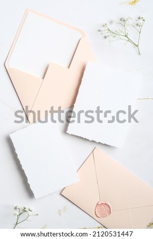 Wedding stationery set. Blank paper cards templates, envelopes with seal stamp, flowers on marble table. Flat lay, top view.