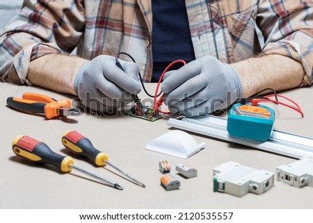  Electrician repairing lights on desk. Technician use multi meter.