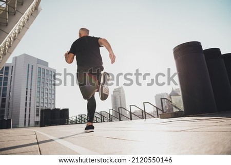 Rear back view photo of motivated man run circle stadium keep fit body shape wear t-shirt urban town outdoors