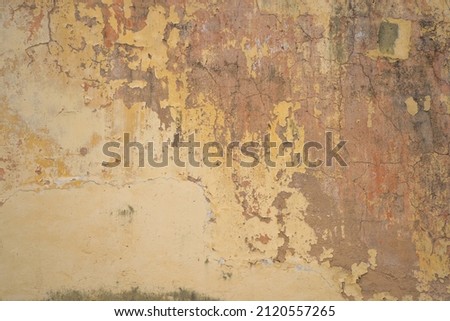 Texture of old yellow concrete wall for background. Rust​ damaged​ to​ surface​ wall​ concrete​ for​ background​. Rough texture on yellow wall rough form due to peeling paint layer due to rain. 