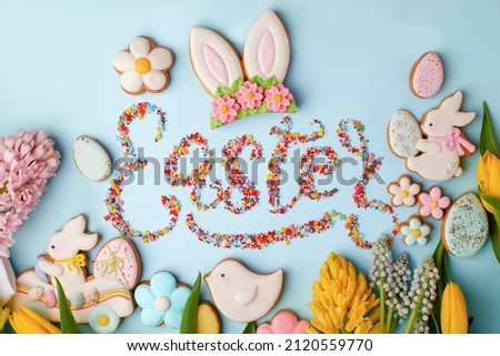 Food Lettering EASTER Colorful easter cookies and flowers tulip on blue background, assortment sweet gifts, seasonal springtime holiday greeting card, creative idea for decor, flyer, invitation