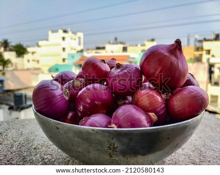Pile of fresh organic pink color onion kept in steel container or bowl under bright sunlight. Picture captured at Bangalore, Karnataka, India. focus on object.
