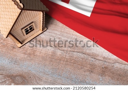 House model near Tonga flag. Real estate sale and purchase concept. Space for text.