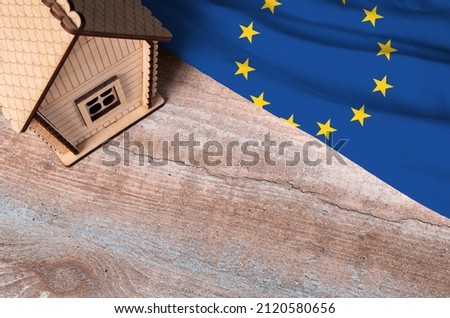 House model near European union flag. Real estate sale and purchase concept. Space for text.
