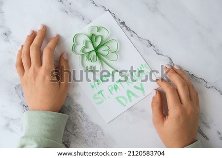 Gift idea, decor Spring, happy Patrick Day. Step by step. Diy St. Patricks Day greeting card made of Quilling and paper clovers on white background. Top view. Process kid children craft Do it yourself