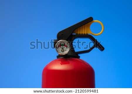 Fire extinguisher pressure gauge. Close up studio shot, isolated on blue background, no people.