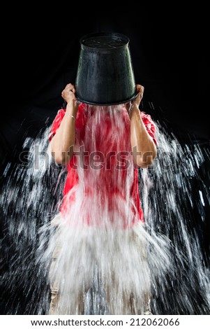 man pour a bucket of ice topped their head on a black background.