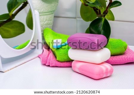 a stack of towels soap toothbrush mirror and houseplant on the bathroom table. High quality photo