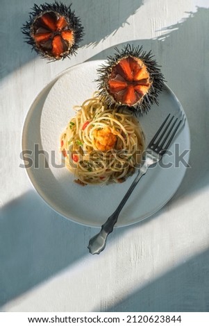 Pasta spaghetti with sea urchins (ricci di mare) or uni in the white plate on the white wood, light and shadows. Summer mood still life.  Delicious seafood pasta from southern Italy: Sicily Royalty-Free Stock Photo #2120623844