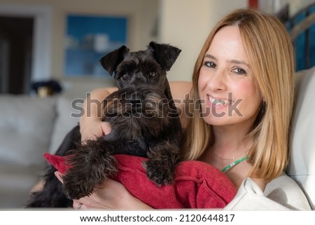 Close up portrait of young smiling woman with her cute schnauzer at home. Animal communication concept