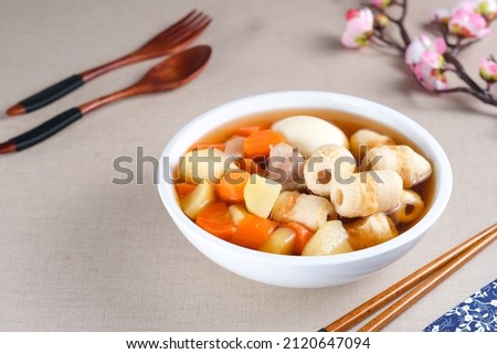 Traditional Japanese Oden with radishes, carrots, potatoes, chikuwa, meatball, fish cakes and boiled egg of food stewed in a white bowl. Selective focus.