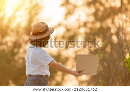 Asian woman wear white shirt backpack waiting car transportation.
woman holding paper sign. sunset time.