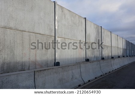 soundproof wall made of concrete porous ribbed material. fence of gray blocks embedded in metal beams, on street. road traffic noise  garden and residential area. protection of Jerusalem, rocket Royalty-Free Stock Photo #2120654930