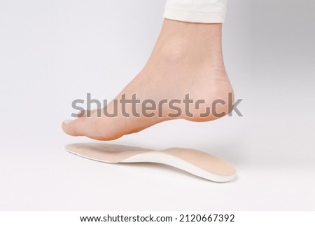 Medical insoles. Isolated orthopedic insoles on a white background. Foot care. Insole cutaway layers. Leg hanging over the insole. Treatment and prevention of flat feet and foot diseases. Royalty-Free Stock Photo #2120667392