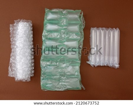 A pimply bag, and air cushions for packing fragile parcels on a brown background. Various types of polypropylene packaging bags. Bubble wrap and perforated airbags for transporting goods.  Royalty-Free Stock Photo #2120673752