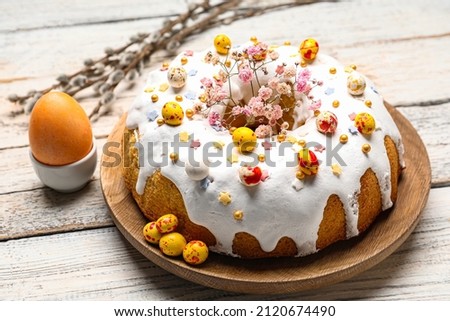 Plate with tasty Easter cake and egg on white wooden background