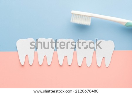 Brushing teeth and oral hygiene concept. Creative idea of tooth shape made from paper with toothbrush on pink and blue background. Dental care.