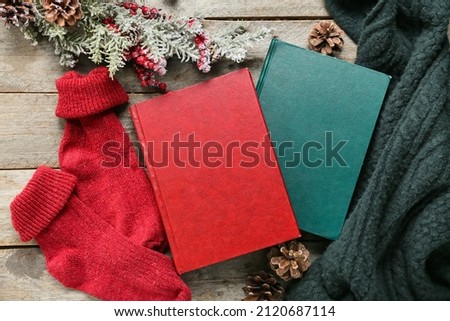 Books, knitted clothes and winter decor on wooden background