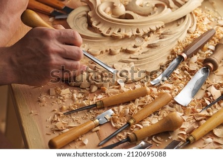 Wood carving. Carpenter's hands use chiesel. Senior wood carving professional during work. Man working with woodcarving instruments Royalty-Free Stock Photo #2120695088