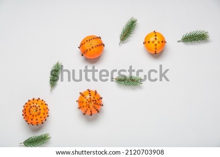 Handmade Christmas decoration made of tangerines with cloves and fir branches on light background