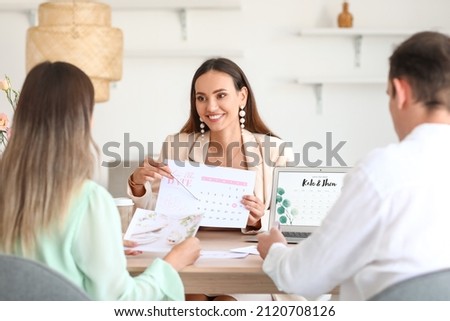 Female wedding planner discussing ceremony with clients in office Royalty-Free Stock Photo #2120708126