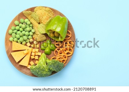 Wooden board with different products for St. Patrick's Day celebration on blue background