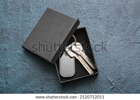 Box with stylish keys and keychain on dark background