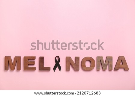 Word MELANOMA and black ribbon on pink background. Melanoma concept