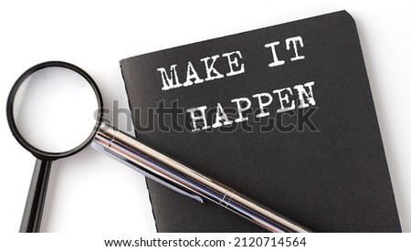MAKE IT HAPPEN - business concept, magnifier with white text message on black notebook