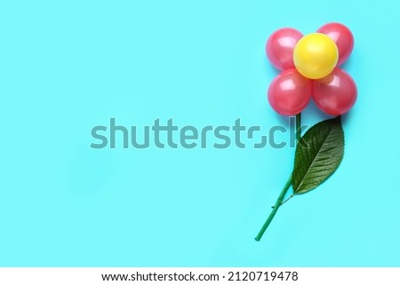 Flower made of balloons and leaf on blue background