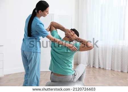Orthopedist helping patient to do exercise in clinic. Scoliosis treatment Royalty-Free Stock Photo #2120726603