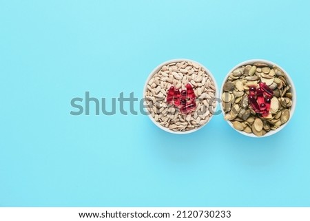 Bowls with pumpkin, sunflower seeds with pills on color background