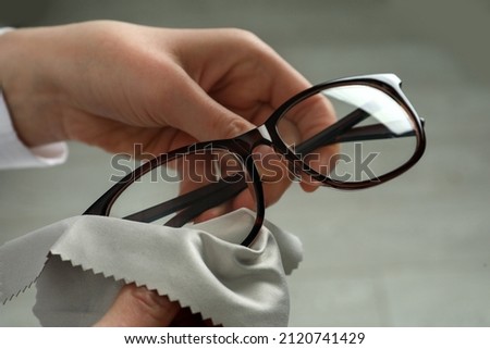 Woman cleaning glasses with microfiber cloth at home, closeup Royalty-Free Stock Photo #2120741429