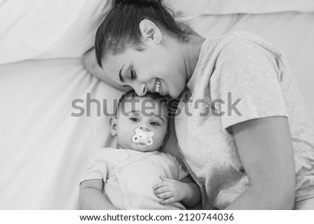 Mother and baby lying in bed - Cute toddler with pacifier