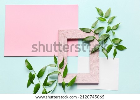 Composition with empty picture frame, blank cards and plant branches on color background