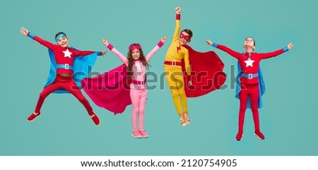 Group of full body boys and girl in colorful superhero costumes clenching fists and pretending to fly while playing isolated on turquoise background Royalty-Free Stock Photo #2120754905