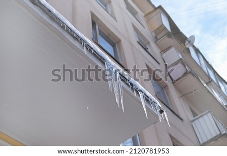 Big icicles above the entrance to a residential building in Moscow. Hanging icicles above the entrance to a building, risk to life. Sharp icicles hang from the roof of an old apartment building Royalty-Free Stock Photo #2120781953