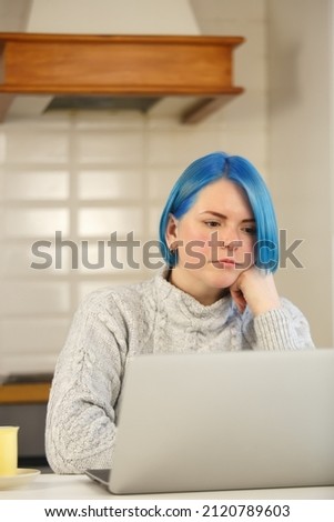 Entrepreneur woman working at home. Focused freelancer female with dyed blue hair thinking about problem solution. Young adult person doing distant work online during lockdown
