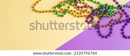 Colorful festive mardi gras or carnivale green, violet and yellow beads, selective focus, copyspace, postcard, banner