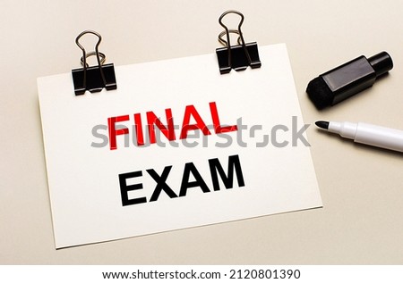 On a light background, a black open marker and on black clips a white sheet of paper with the text FINAL EXAM