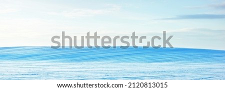 Breathtaking panoramic view of snow-covered field after a blizzard at sunset. Lapland, Finland. Dramatic cloudscape. Winter wonderland. Ice desert. Ecology, weather, climate change, global warming