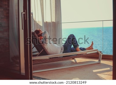 Relaxed young man at home on the balcony. Holiday and travel concept Royalty-Free Stock Photo #2120813249