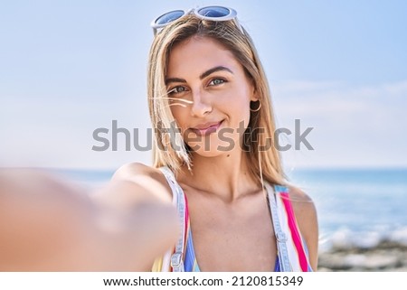 Young blonde girl smiling happy make selfie by the smartphone at the beach.