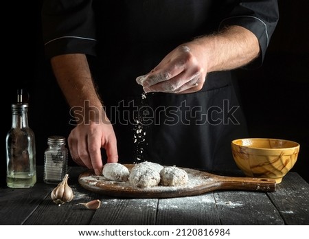 The cook sprinkles flour on cutlets. Cooking meat cutlets by the hands of a chef in the restaurant kitchen. The idea of making a delicious breakfast or lunch