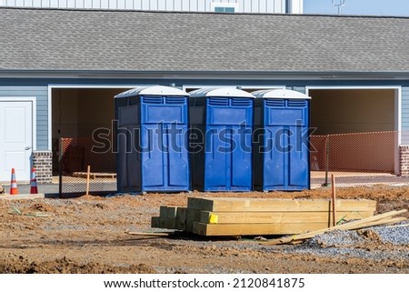 Horizontal shot of three porta potties or outdoor toilets at a new construction site. Royalty-Free Stock Photo #2120841875