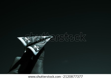 An airplane made of a dollar. The background is dark. High quality photo. An airplane made of a dollar. The background is dark.