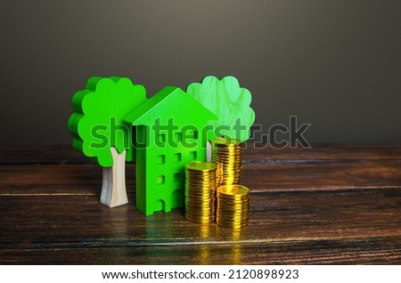 Growing stacks of coins and a green house. Economy and efficiency of green technology in housing. Investment grants and funding. Autonomy and self-sufficiency. Negative carbon footprint. Royalty-Free Stock Photo #2120898923