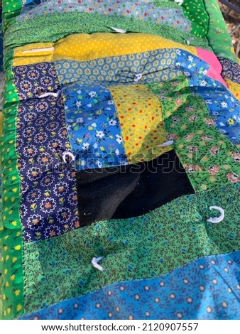 Close up of patchwork quilt with green, blue, yellow, pink, black fabric